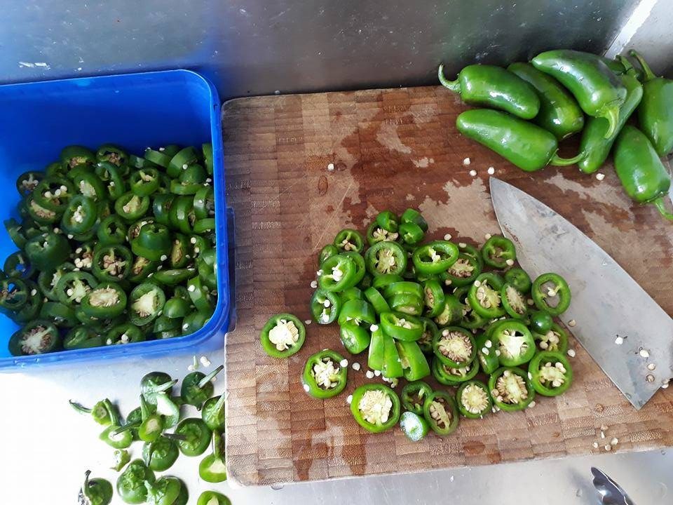 A chopping board covered in sliced jalapeno peppers